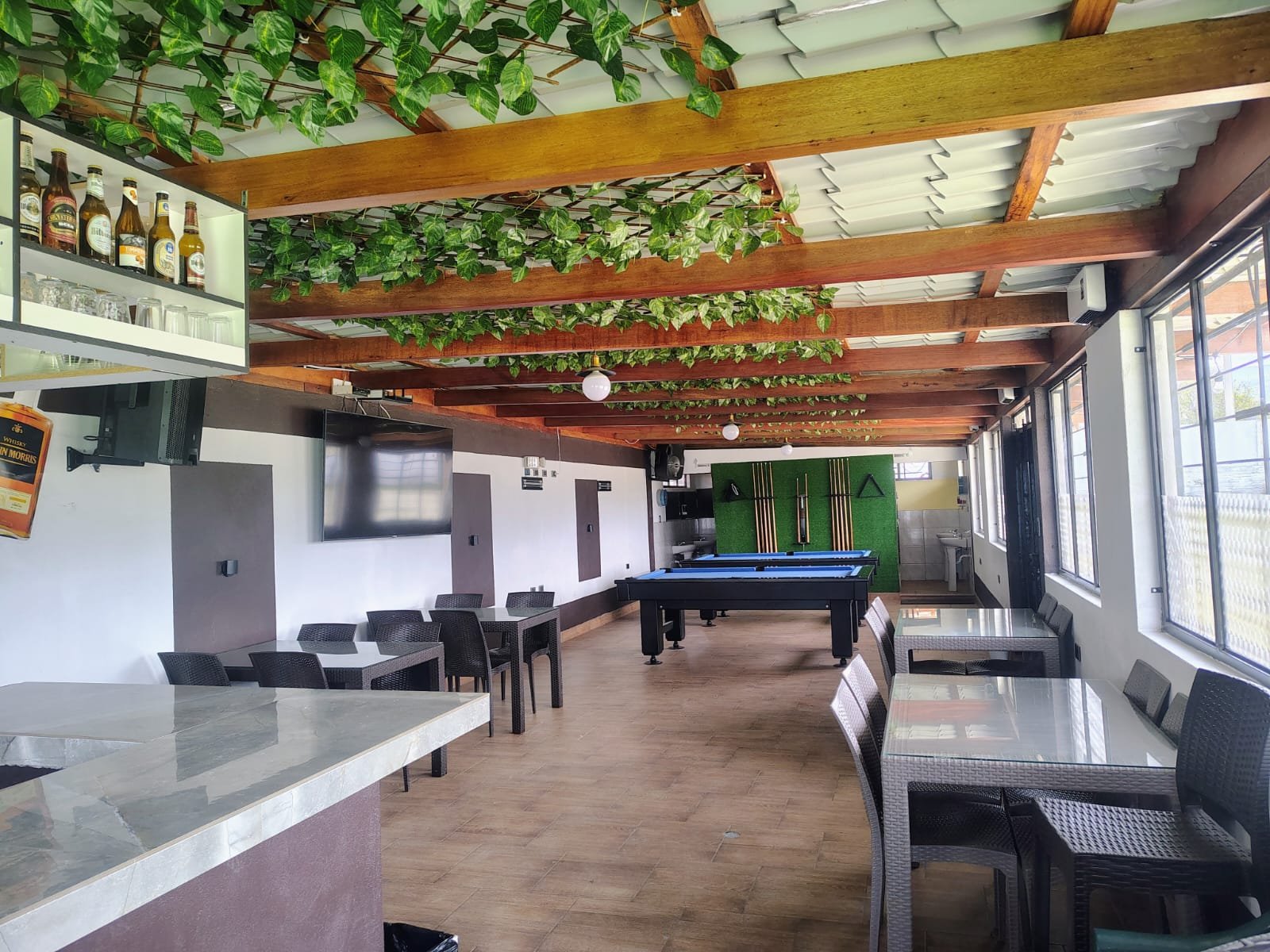 Interior de un bar con barra, mesas y billar.